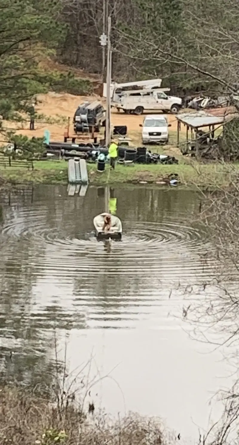 Crew member wading through floodwater on a restoration job, trucks staged behind
