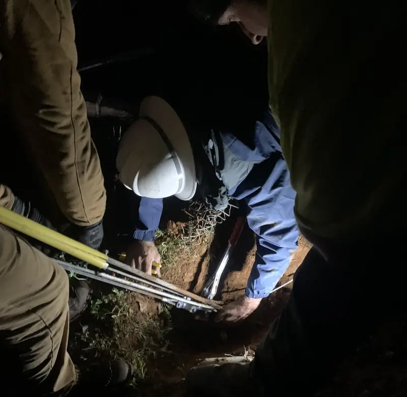 Crew digging by flashlight during a night restoration
