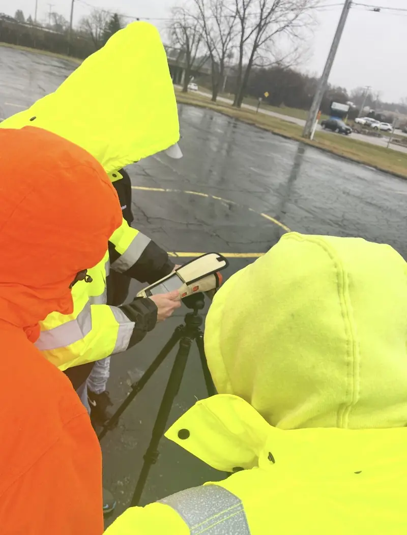 Crew in rain gear taking GPS survey shots in the rain
